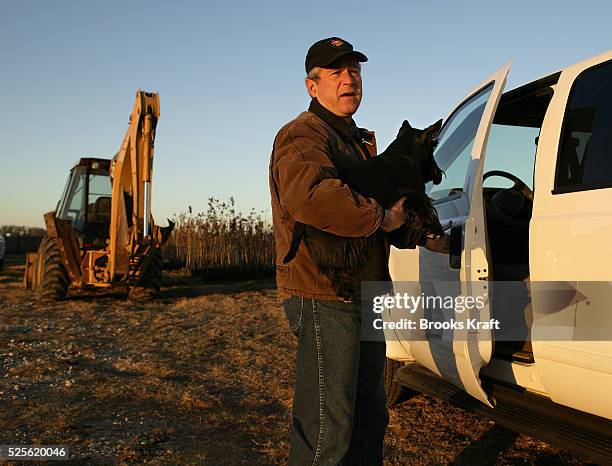 President George W. Bush carries his dog Barney as he prepares to drive to his daily intellegence briefing on the Bush Ranch in Crawford, Texas.