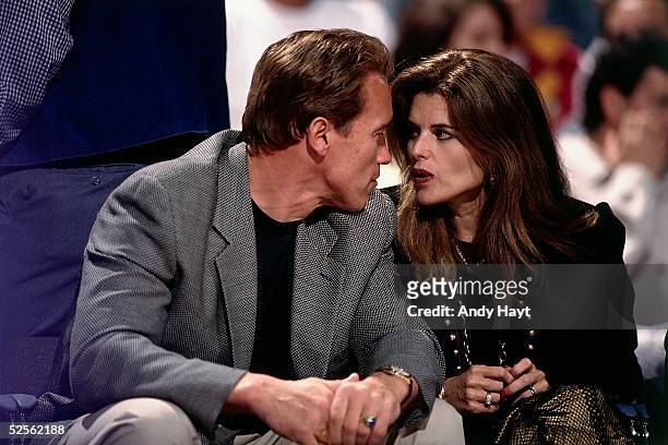 Celebrity Arnold Schwarzenegger and wife Maria Shriver talk during an NBA game on April 18, 1995 at the Forum in Los Angeles, California. NOTE TO...
