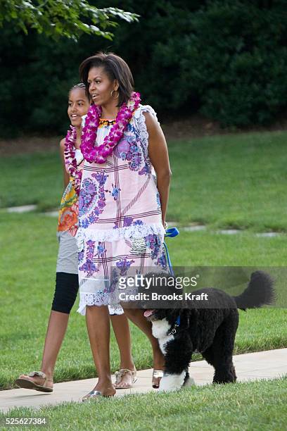 First lady Michelle Obama and daughter Malia walk from the Oval Office with their dog Bo as they attend a luau, or Hawaiian feast, on the South Lawn...