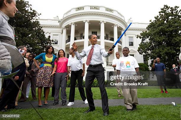 President Barack Obama uses a light saber as he watches a demonstration of fencing at an event supporting Chicago's 2016 host city Olympic bid, on...