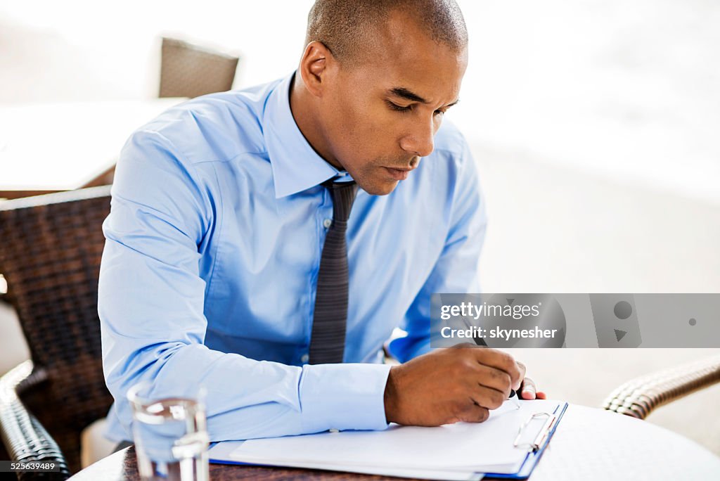 Afro americano Uomo d'affari di scrivere un documento aperto.