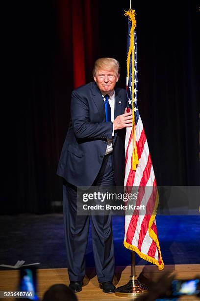 Republican presidential candidate Donald Trump hugs an American flag while attending a town hall in Derry, N.H