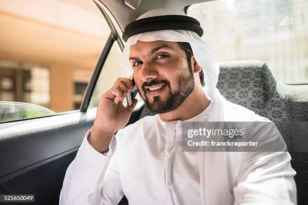 jeque por teléfono en el interior de un taxi - emirati face smile fotografías e imágenes de stock