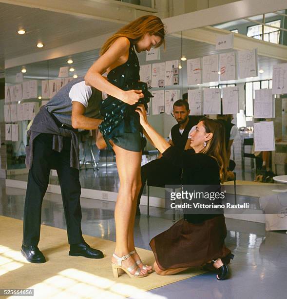 Italian fashion designer Miuccia Prada adjusting clothes on Italian-French top model Carla Bruni.