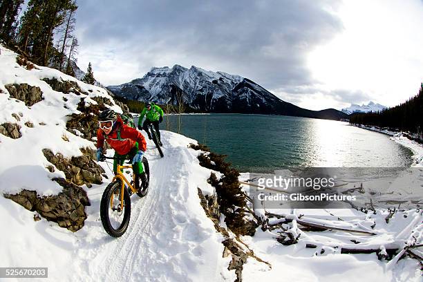 snow biking couple - winter stock pictures, royalty-free photos & images