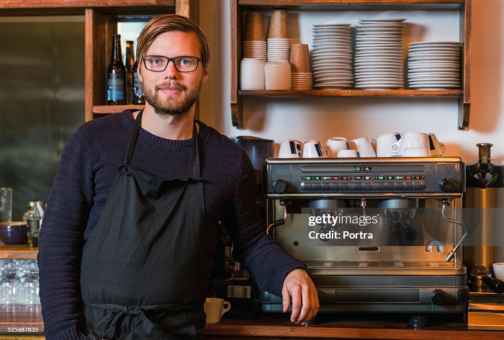 Confident male barista standing in restaurant