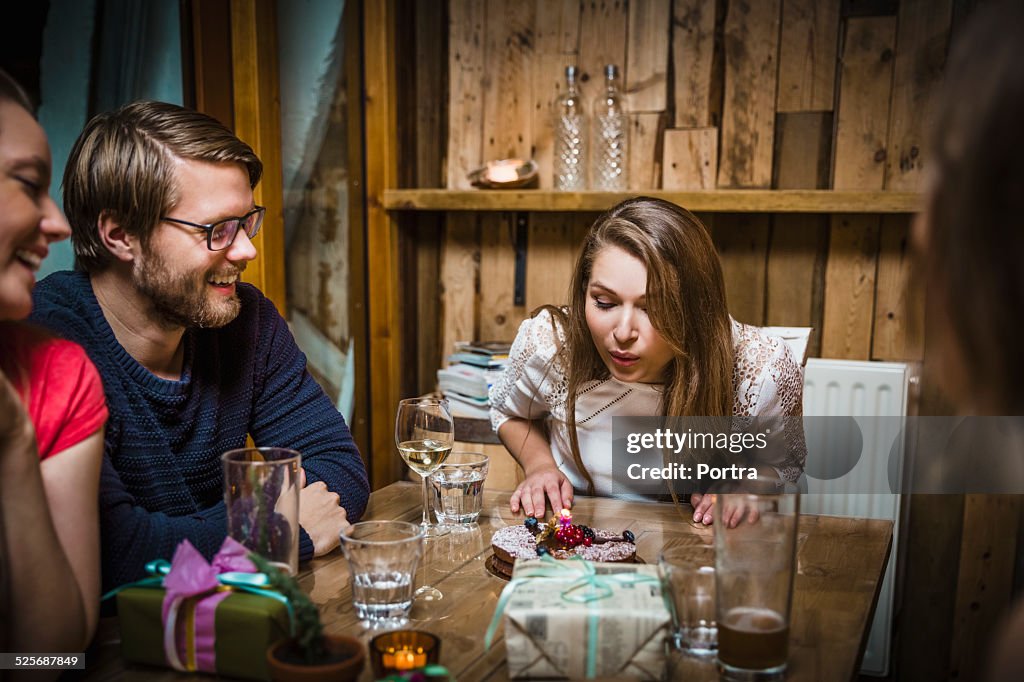 Woman blowing candles on cake in restaurant