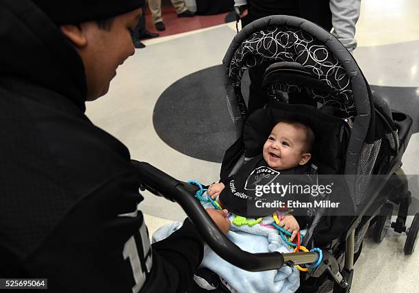 Delphino Rubi IV of Nevada looks at his four-month-old son Delphino Rubi V, dressed in Oakland Raiders gear, as fans wait for Raiders owner Mark...