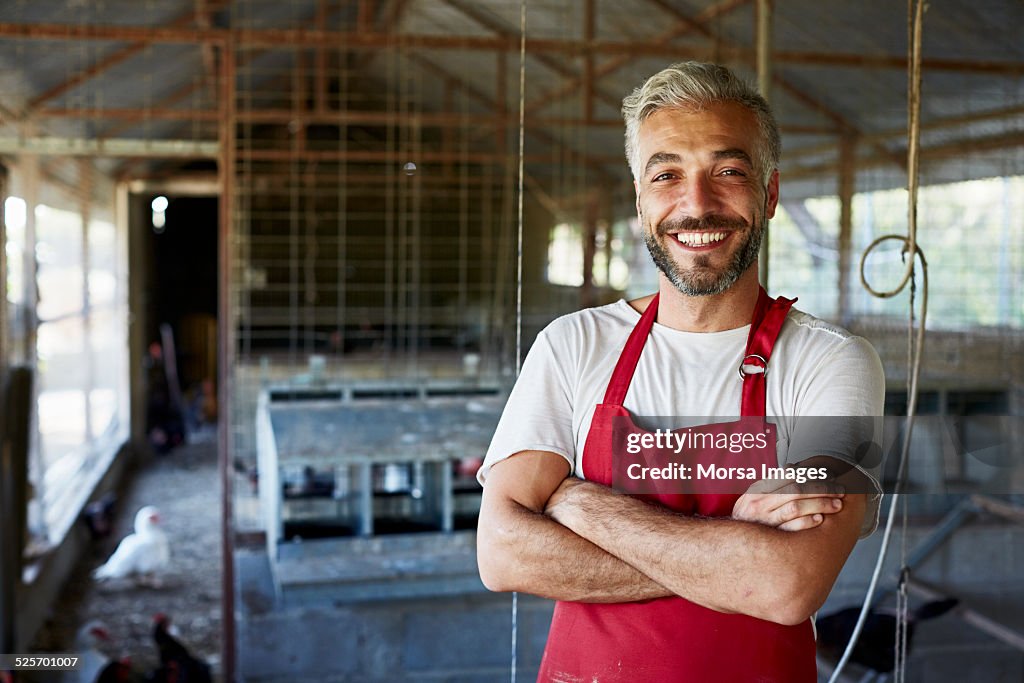 Happy worker standing at poultry farm