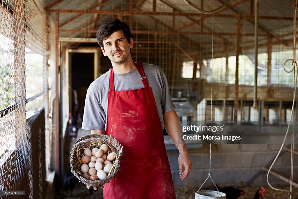 Worker holding egg basket at poultry farm