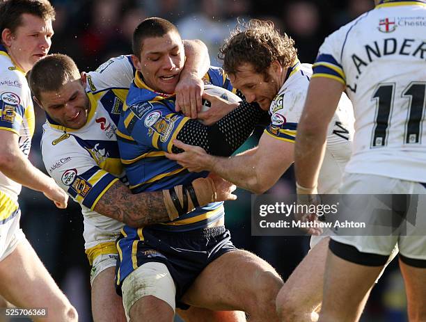 Ryan Hall of Leeds Rhinos gets tackled by Paul Wood and Michael Monaghan of Warrington Wolves