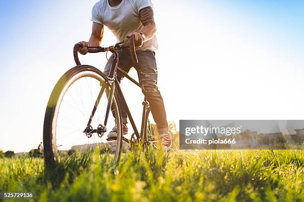hipster garçon d'équitation de bicyclette sur l'herbe - pantalon déquitation photos et images de collection