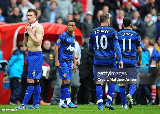 Phil Jones and Nani of Manchester United look up at the scoreboard to see Manchester City 3-2 QPR as Wayne Rooney and Ryan Giggs walk off as they...