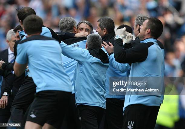 Roberto Mancini the head coach / manager of Manchester City is mobbed by staff at the end of the match