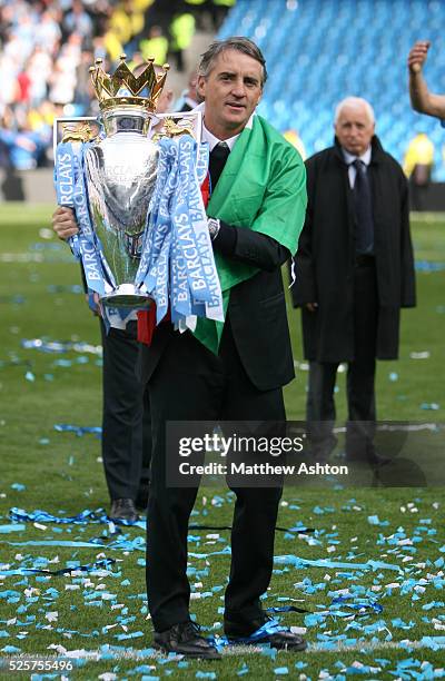 Roberto Mancini the head coach / manager of Manchester City lifts the Barclays Premier League Trophy after beating Queens Park Rangers 3-2 to become...