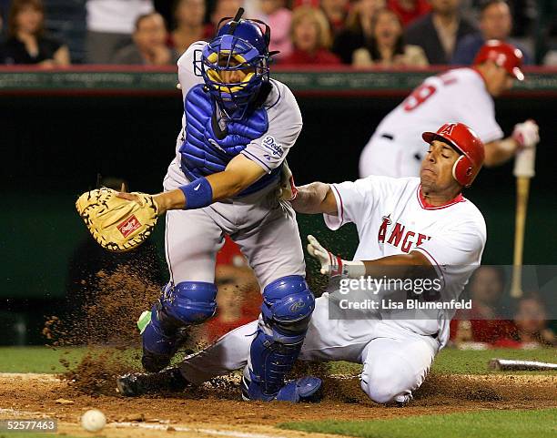 Juan Rivera of the Los Angeles Angels of Anaheim slides into home plate safe against catcher Paul Bako of the Los Angeles Dodgers during the seventh...