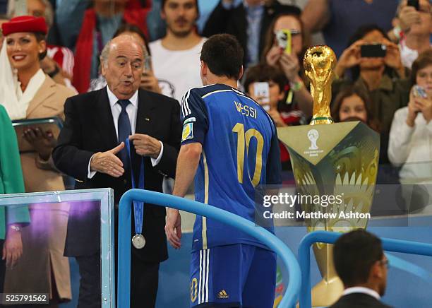 Joseph Sepp Blatter the President of FIFA presents losing captain Lionel Messi of Argentina with his losers medal