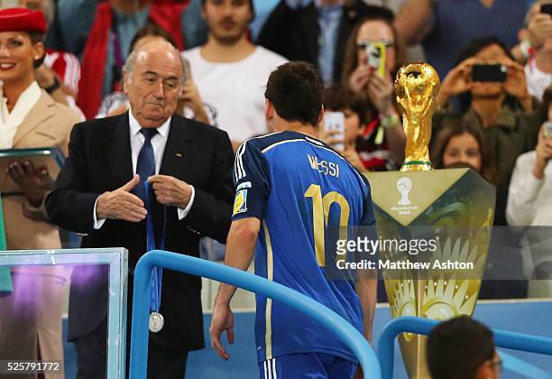 Joseph Sepp Blatter the President of FIFA presents losing captain Lionel Messi of Argentina with his losers medal
