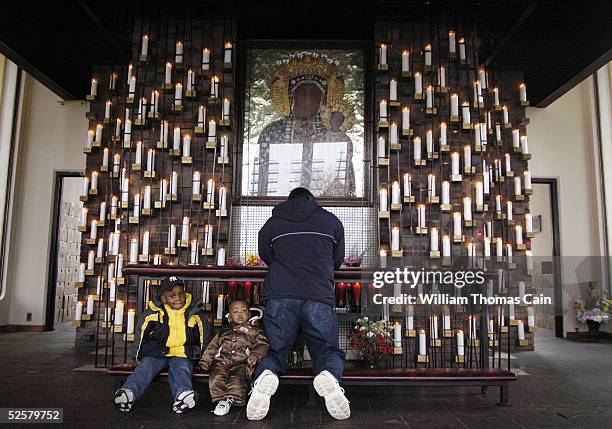 Rodney Chery, Sebastien Chery, 9-months-old, and their father Rony Chery, of Haiti pray for Pope John Paul II in the Candlelight Chapel at the...