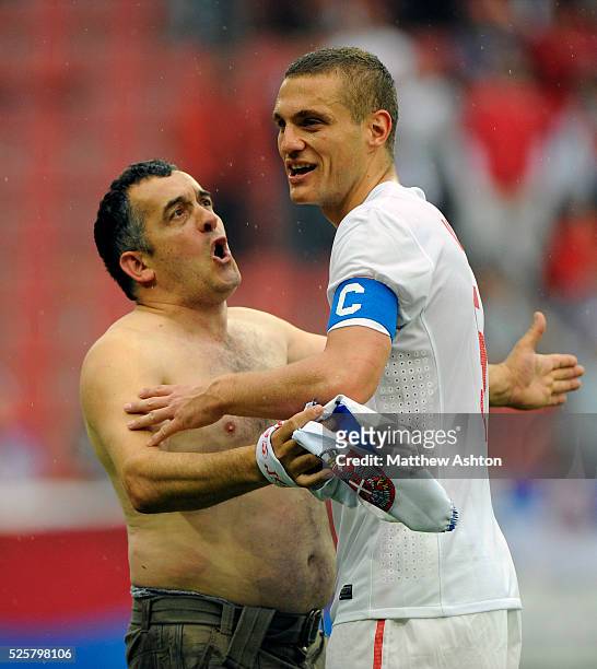 Hooligan from Serbia argues with Manchester United and Serbia captain Nemanja Vidic as he appeals to the crowd to stop throwing objects and running...