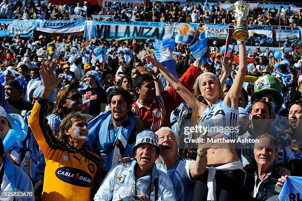 Female fan of Argentina holding up a replica of the FIFA World Cup trophy