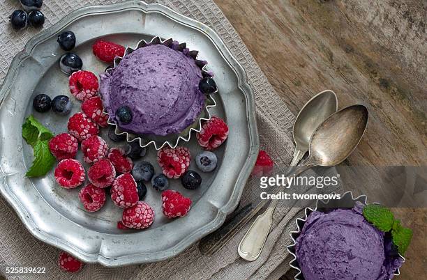 blueberry ice cream served with fresh berries on moody rustic wooden table top. overhead view. - blue bowl fotografías e imágenes de stock