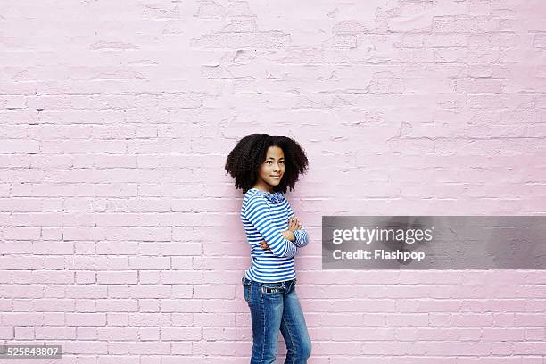 girl leaning against wall - kids standing crossed arms stock-fotos und bilder