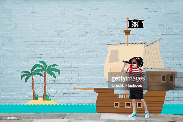 boy dressed as a pirate with cartoon ship - pirate hat stock pictures, royalty-free photos & images