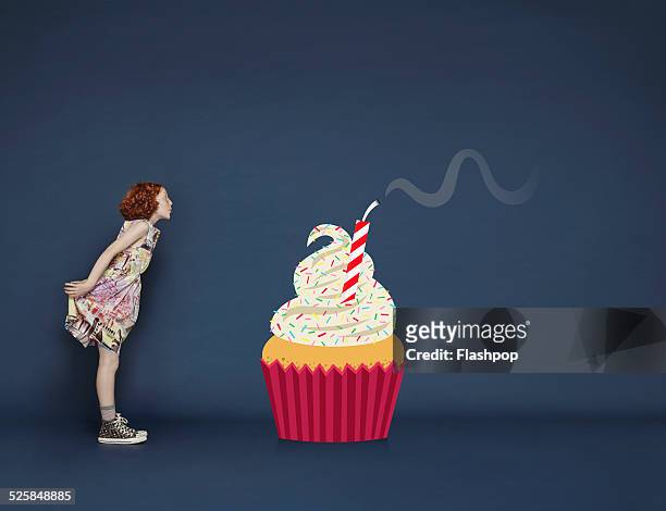 girl blowing out candles on cartoon birthday cake - cupcakes girls fotografías e imágenes de stock