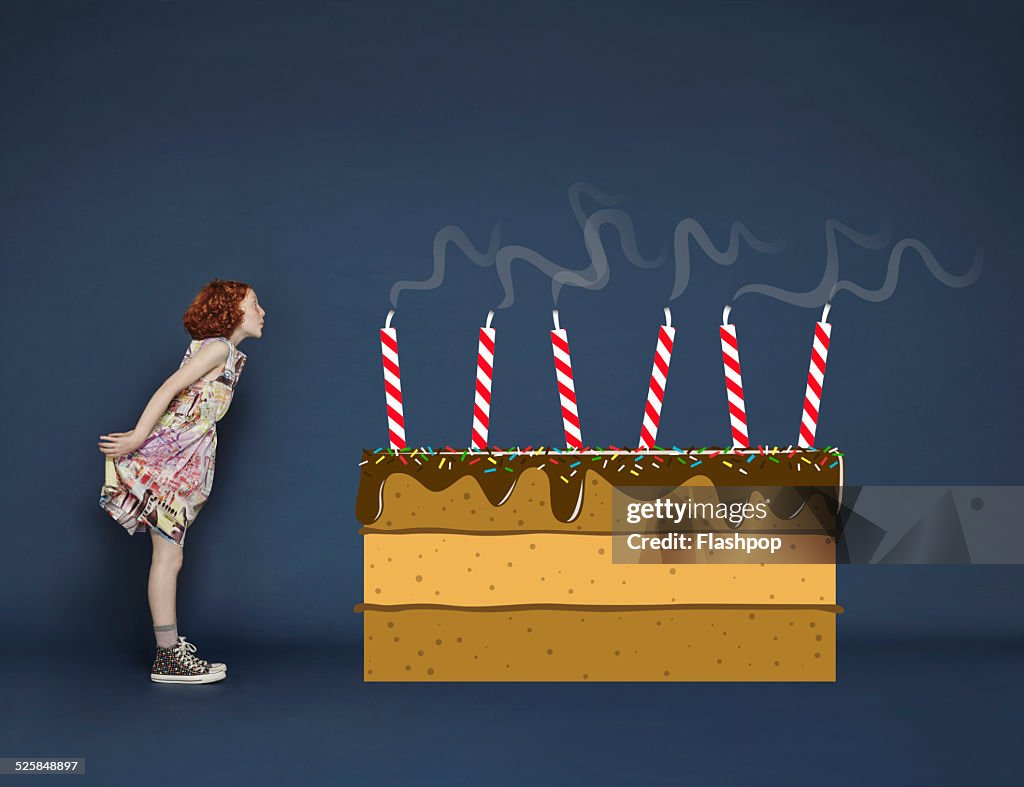 Girl blowing out candles on cartoon birthday cake