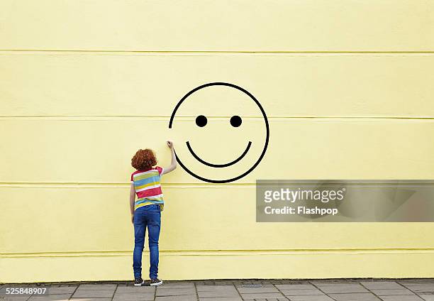 girl drawing smiley face on to a wall - positive emotionen stock-fotos und bilder