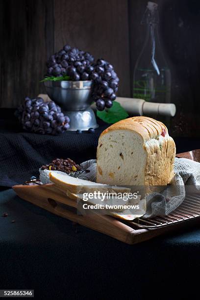 raisin bread loaf served on traditional cake stand on moody rustic wooden kitchen. table top view. - raisin toast stock pictures, royalty-free photos & images