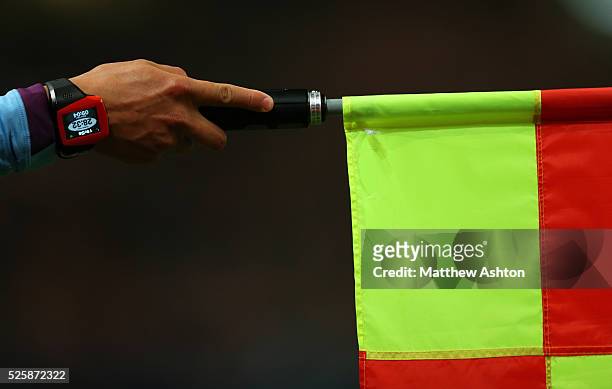 Assistant referee / linesman holding his flag to award offside - wearing a watch showing the time played during a game which through a vibrating...