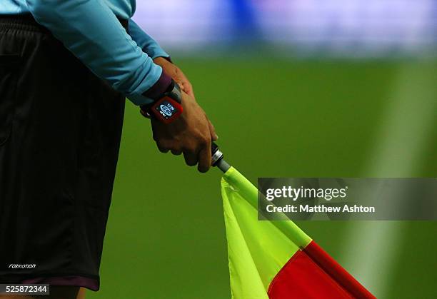 Assistant referee / linesman holding his flag to award offside - wearing a watch showing the time played during a game which through a vibrating...