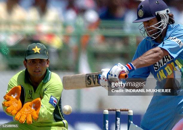 Indian cricketer Mahender Dhoni plays a shot while Pakistani wicketkeeper Kamran Akmal looks on during the second one day international match between...