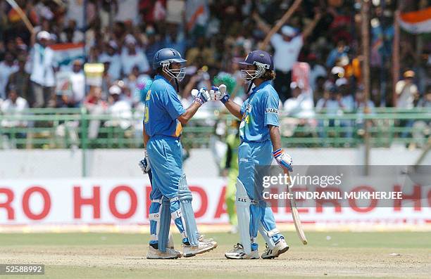 Indian cricketers Mahender Dhoni and Rahul Dravid congratulate each other for their partnership during the second one day international match between...