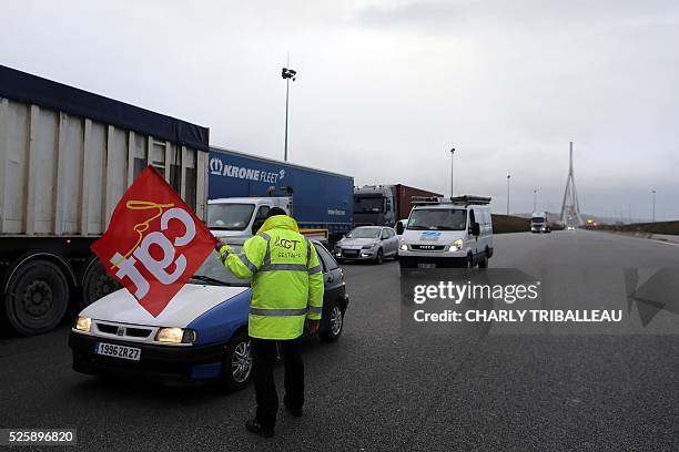 Man holding a flag of the French CGT Trade Union stands guard as he blocks the road at a toll booth on the Normandy Bridge in Le Havre, northwestern...