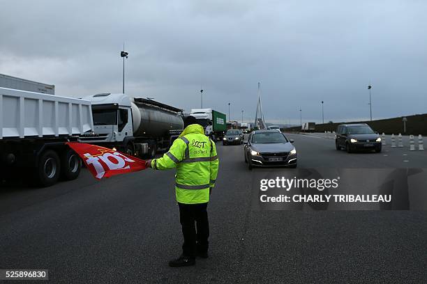 Man holding a flag of the French CGT Trade Union stands guard as he blocks the road at a toll booth on the Normandy Bridge in Le Havre, northwestern...