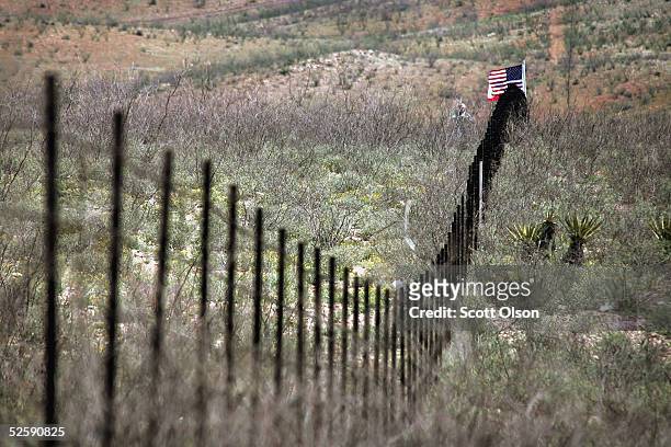 Volunteer from the Minuteman Project stands near an American flag placed in the barbed wire fence which divides the U.S./Mexican border April 4, 2005...