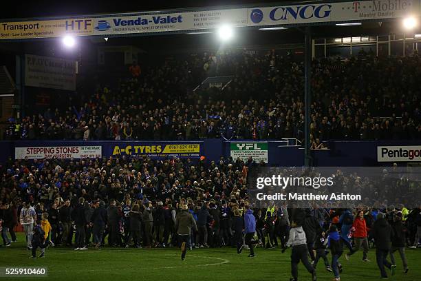 Fans run onto the pitch to celebrate the victory over Liverpool at Boundary Park the home stadium of Oldham Athletic