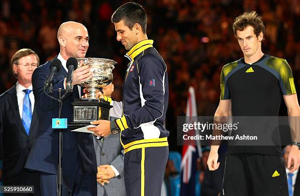 Novak Djokovic of Serbia receives the trophy from Andre Agassi during the Final at the Australian Open, 2013