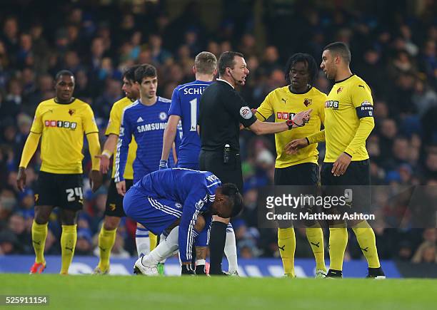 Referee Kevin Friend speaks with Troy Deeney of Watford as Didier Drogba of Chelsea gets up