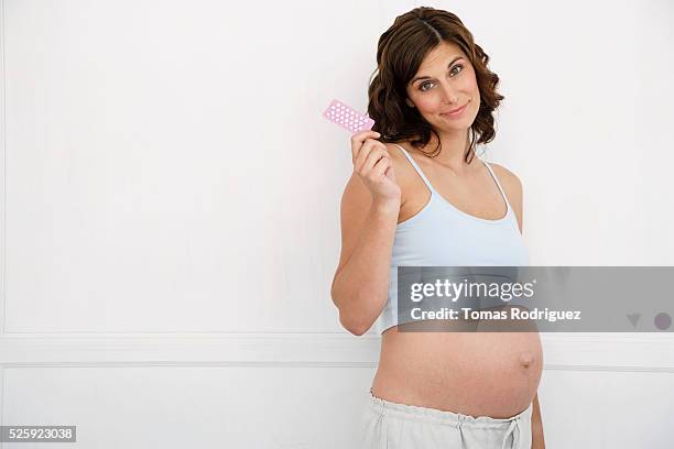 pregnant woman holding birth control pills - hoofd schuin stockfoto's en -beelden