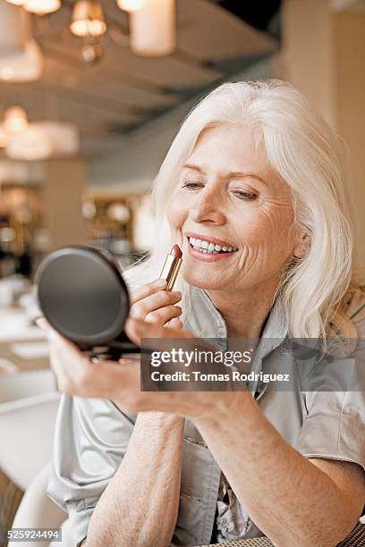 woman applying lipstick in restaurant - entourer photos et images de collection