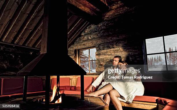 couple relaxing at fireplace in log cabin - sauna winter foto e immagini stock