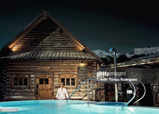 holidaymaker standing outside wooden thermal bath, by swimming pool - sauna winter foto e immagini stock