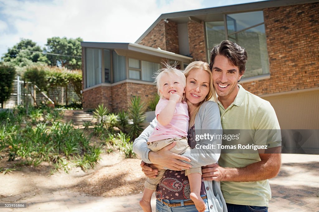 Parents with daughter (12-23 months) in front of house