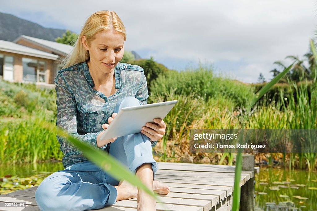 Woman using tablet pc on jetty