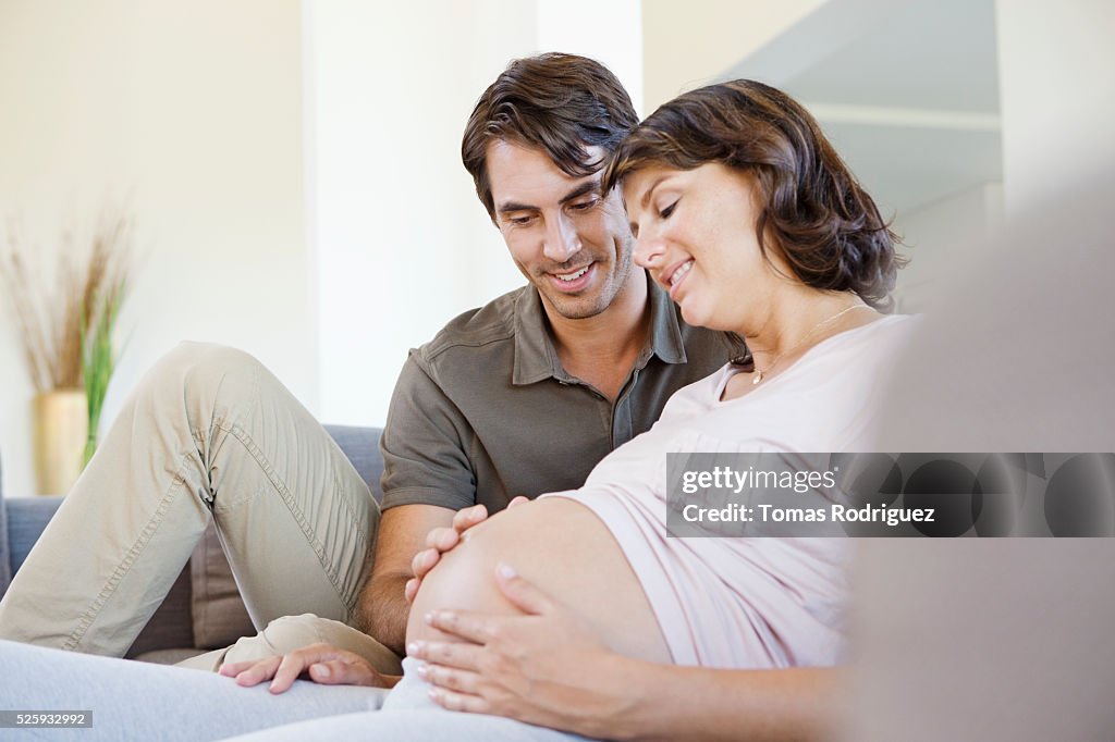 Man and pregnant woman sitting on sofa