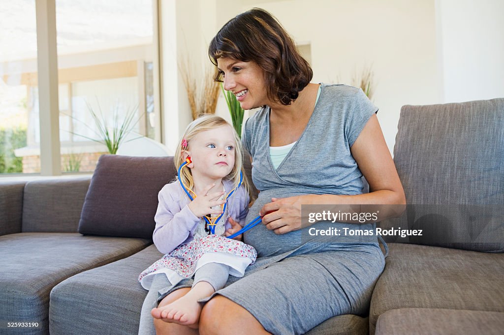 Pregnant woman and girl (2-3) playing in living room